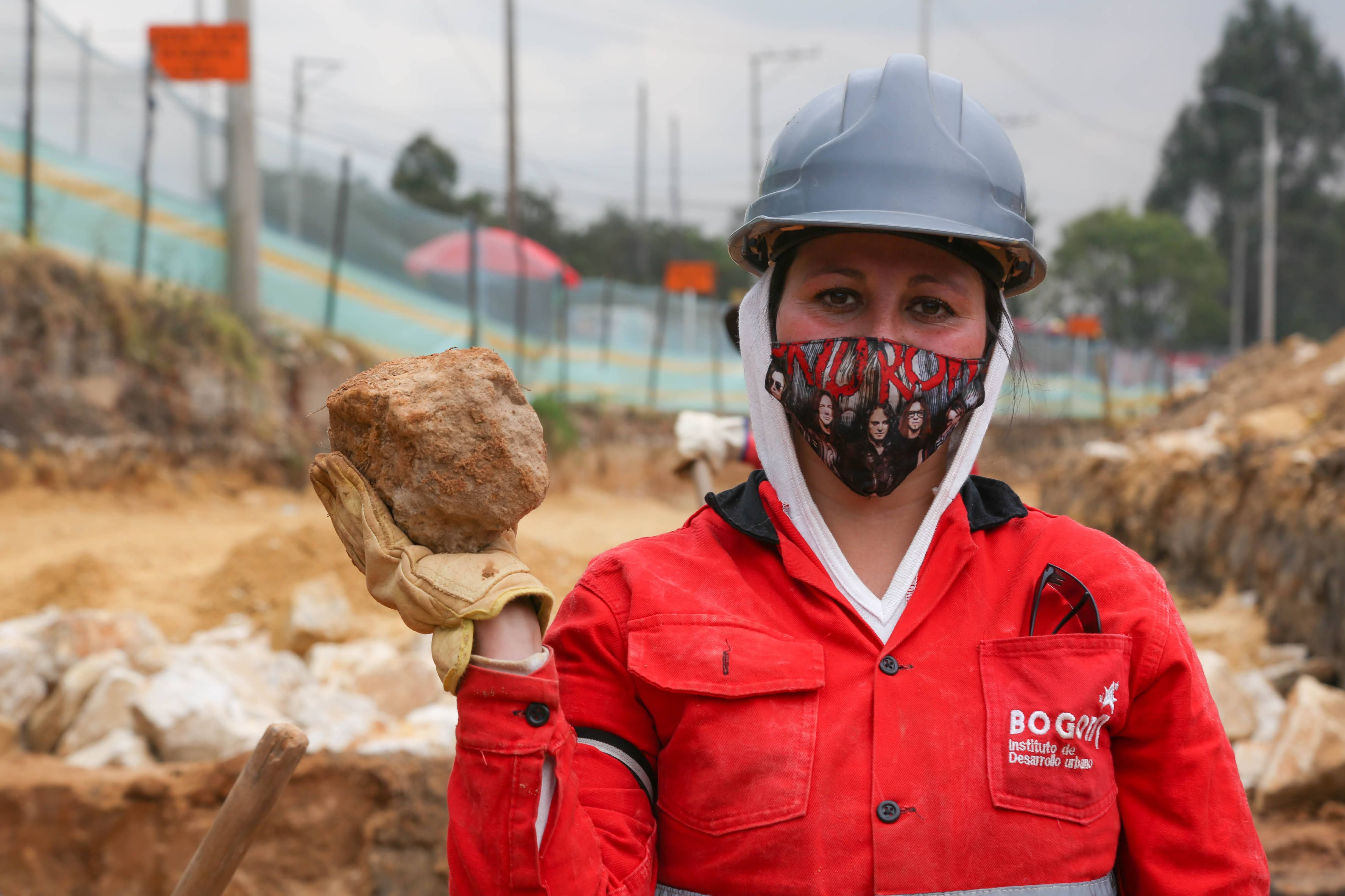 Fotografía de trabajadora con una piedra en la mano en obra del idu 