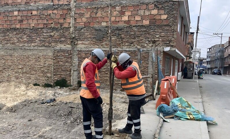 Dos trabajadores abren un hueco en un andén para poder realizar la demarcación de obra