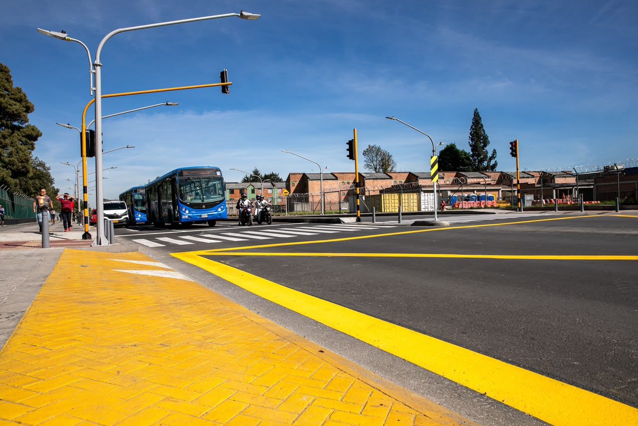 Buses del SITP transitan por la intersección de la avenida calle 63 demarcada con franjas amarillas y paso peatonal.